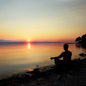 man meditating at sunset