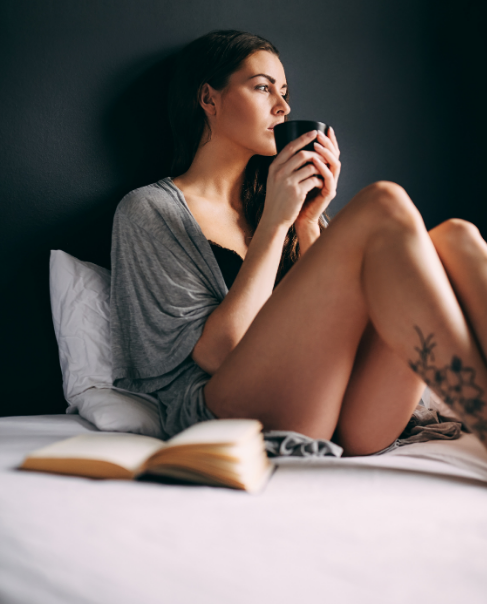 Woman sitting on bed with a mug
