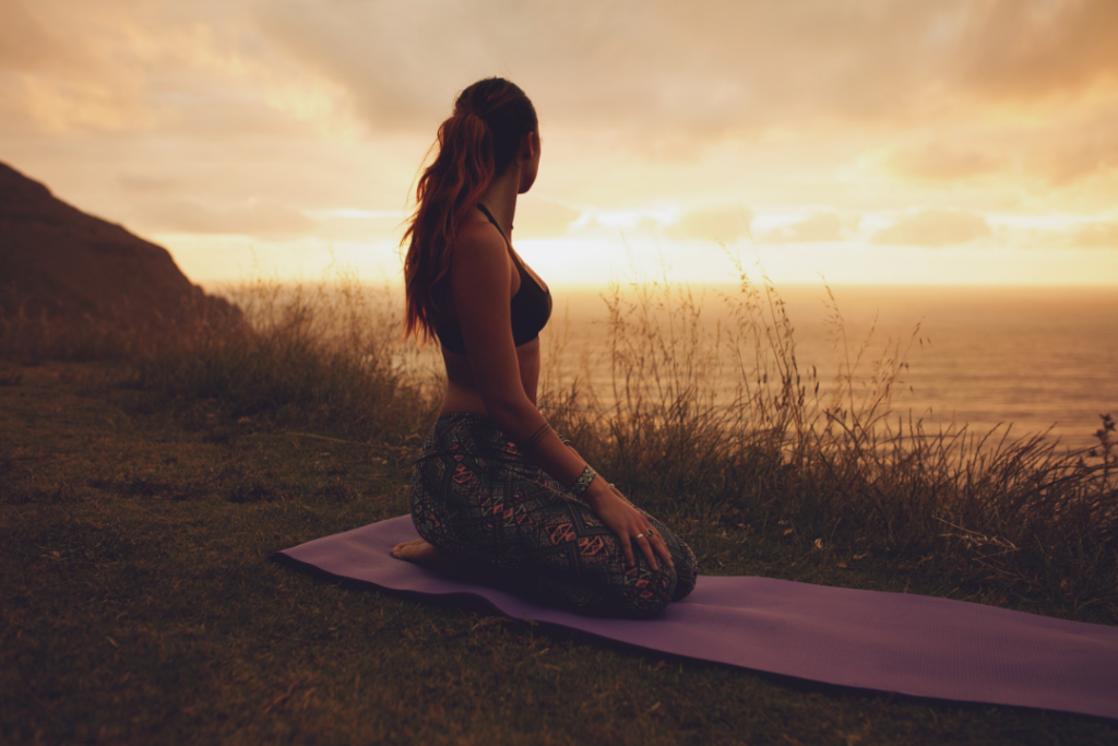 Woman on a yoga mat looking at the ocean