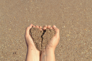 hands holding sand in the shape of a broken heart